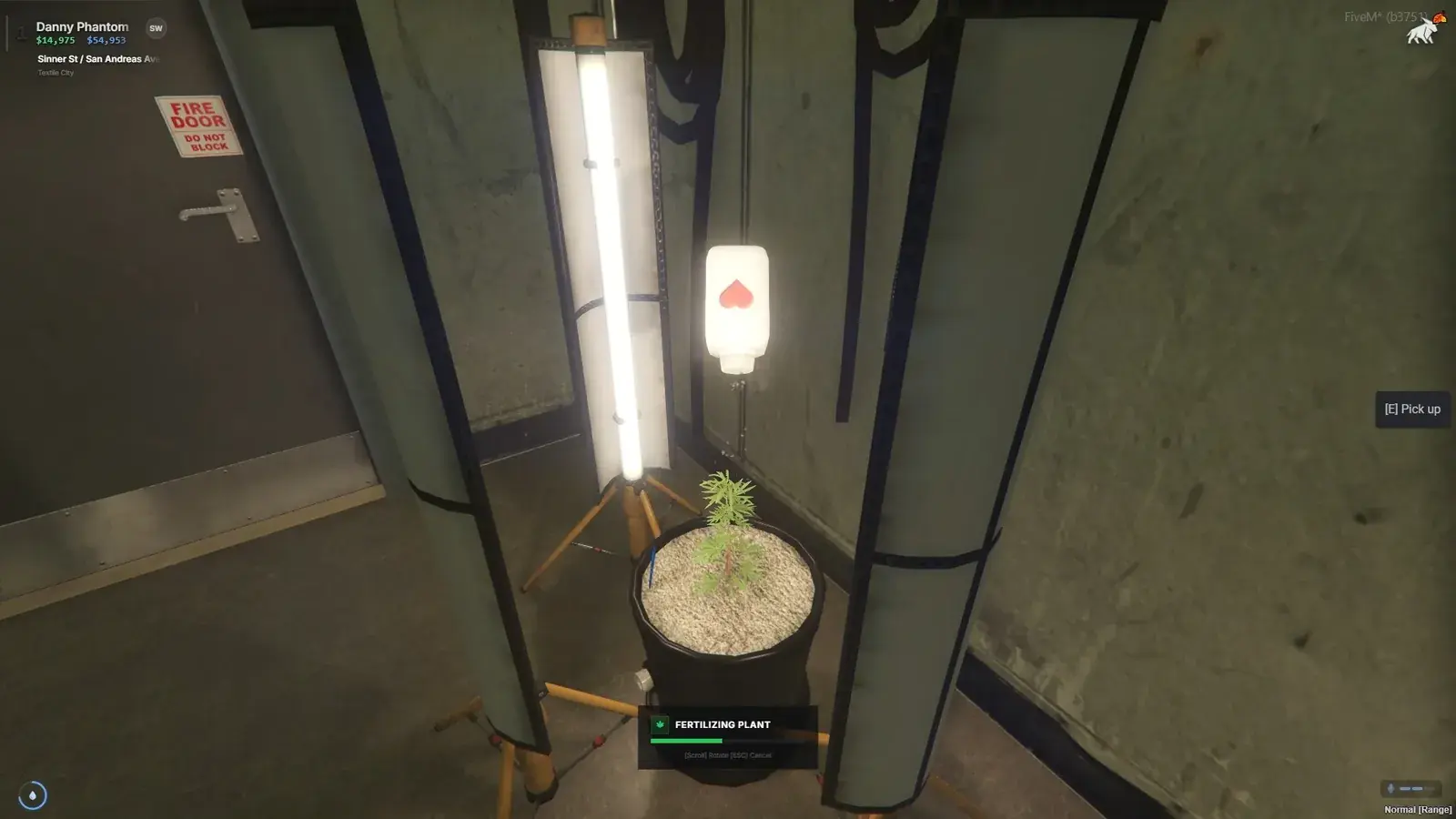 Young cannabis plant in a soil-filled pot beneath a tripod grow lamp inside a grow tent, with a bottle held above it and a Fertilizing Plant progress bar